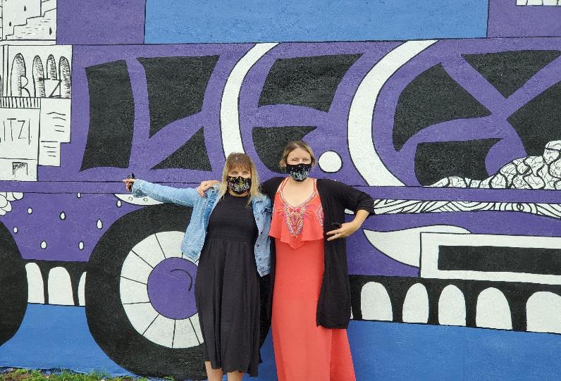 Artist Kelsey Montague (right) poses in front of the new Garfield mural with her sister and partner Courtney